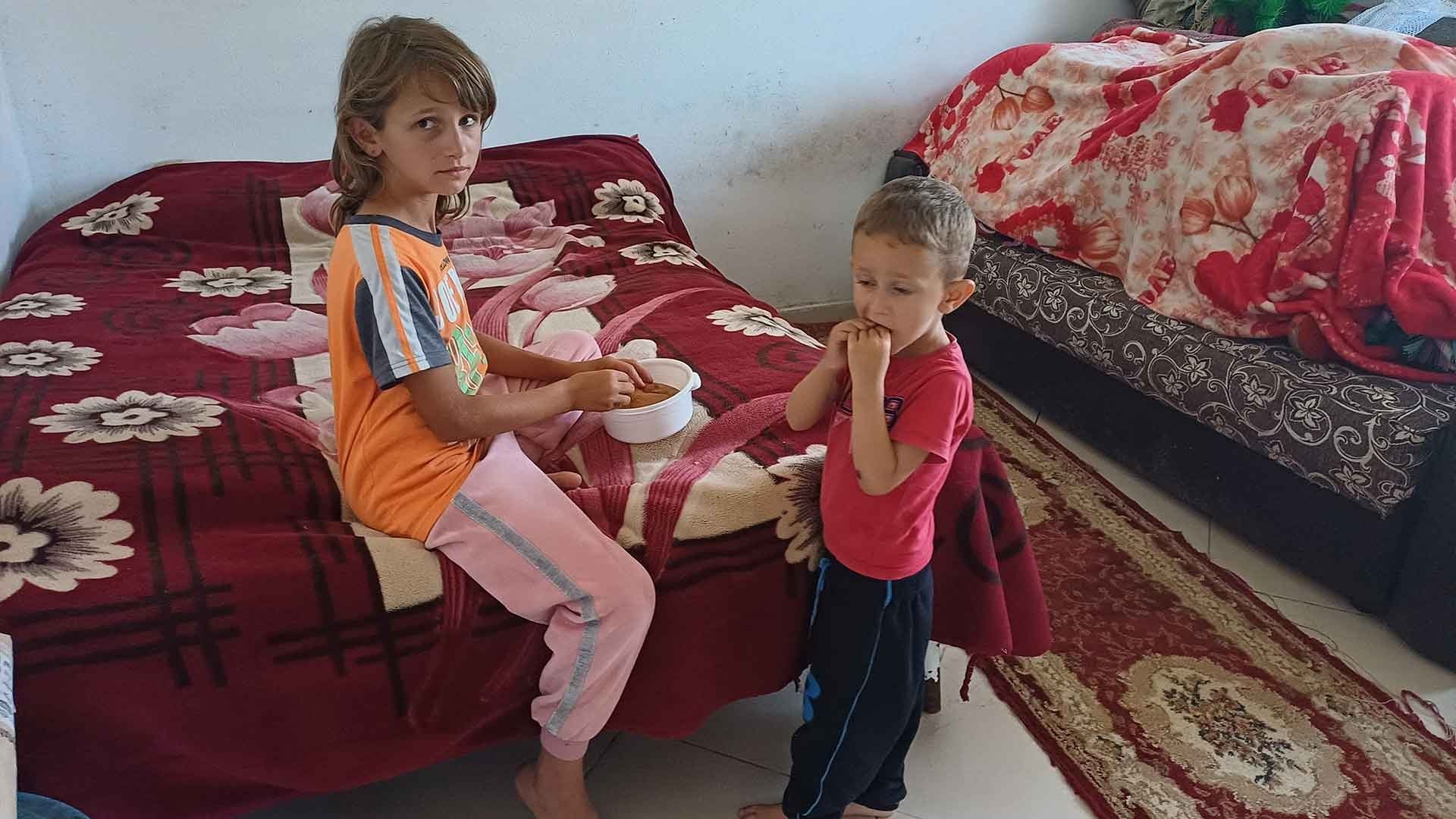 A girl helps feed her little brother.