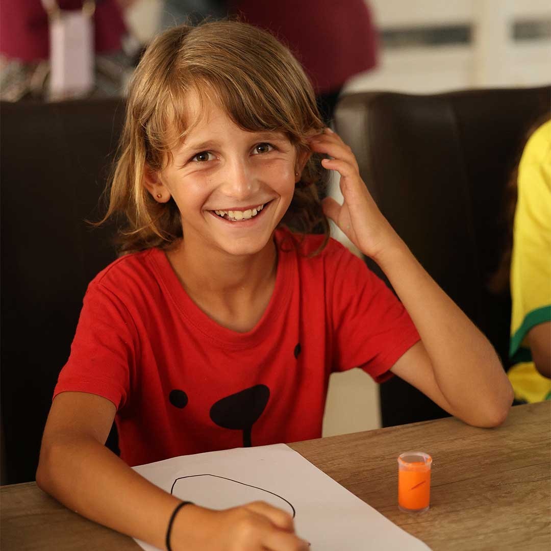 A girl smiles while painting.