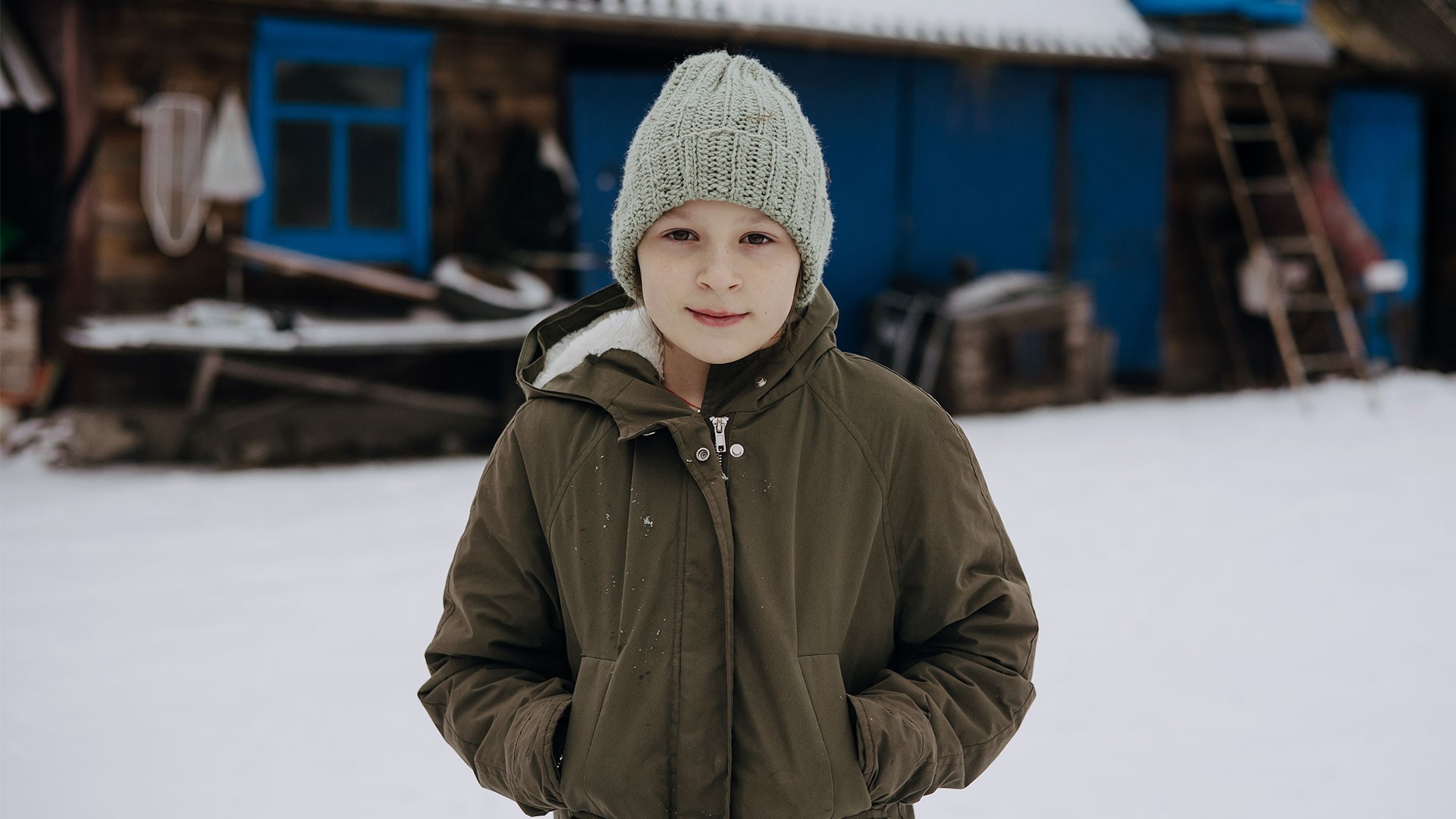 Sofiya stands in snow, looking straight at the camera with a quite smile.
